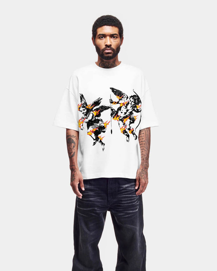 Man wearing a white t-shirt with black and orange angels on fire design and dark jeans on a white background