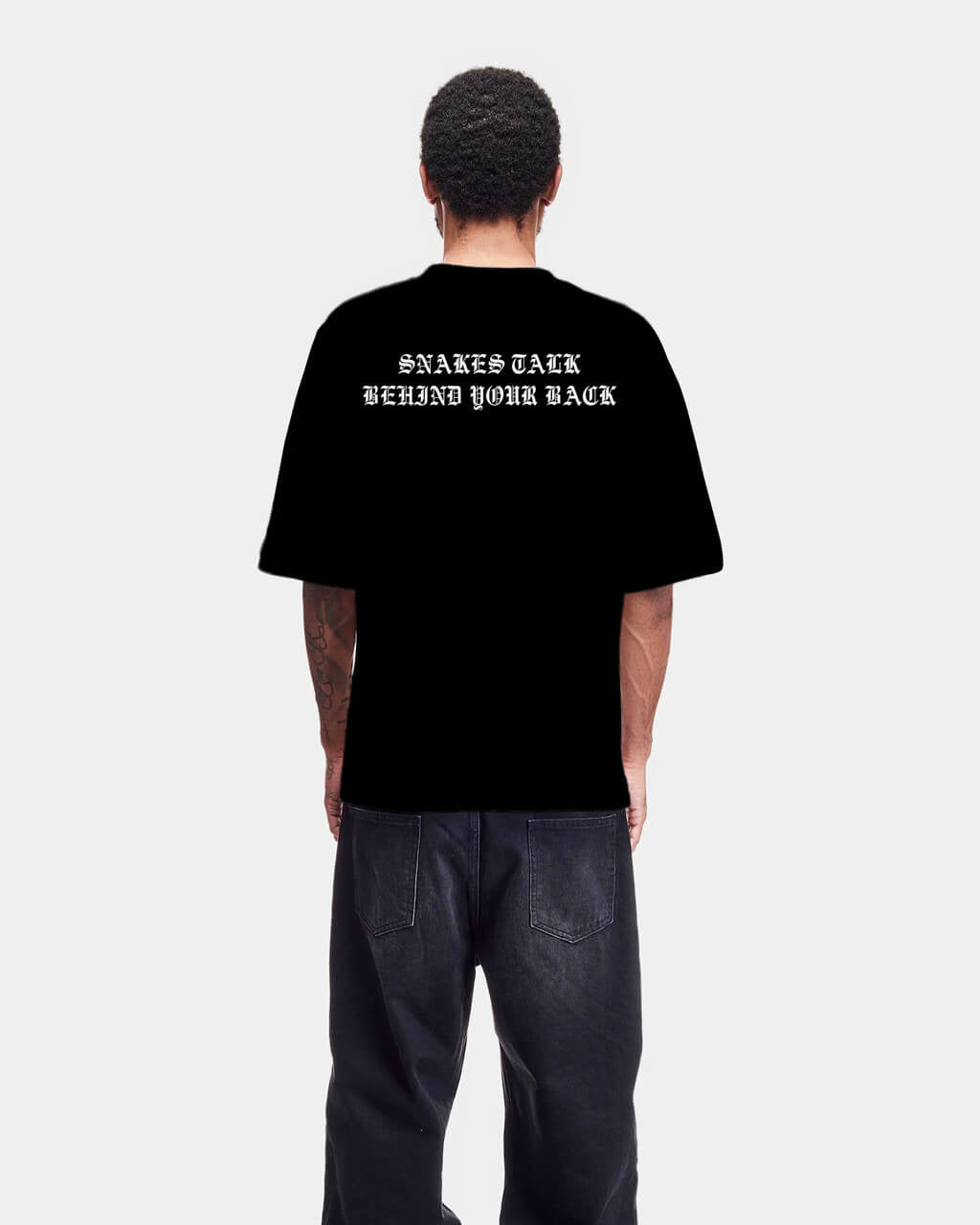 Person wearing a black t-shirt with text on the back, standing against a white background