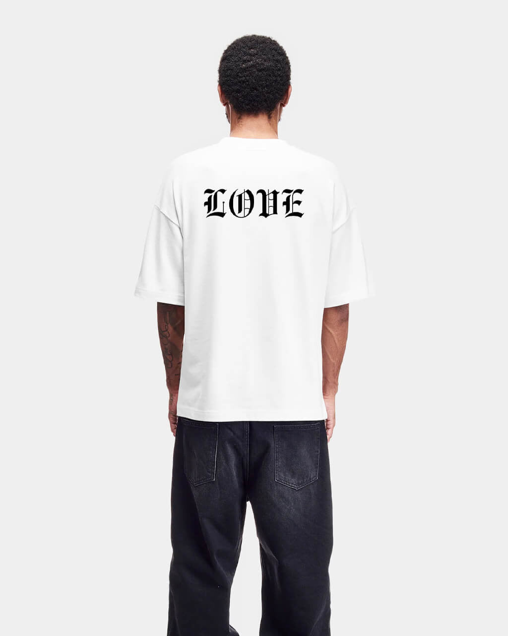 Person wearing a white t-shirt with 'LOVE' printed on the back, standing against a plain background.