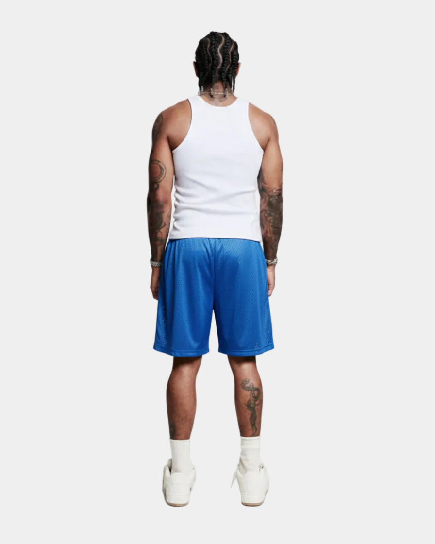 Person wearing a white tank top and blue shorts on a plain background