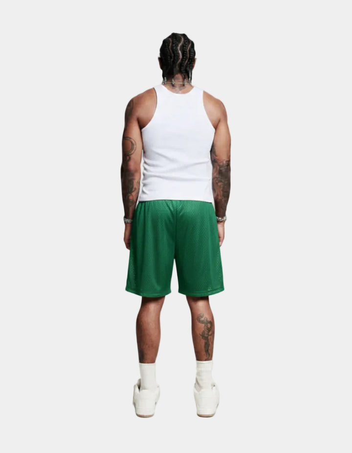Person wearing a white tank top and green shorts on a white background